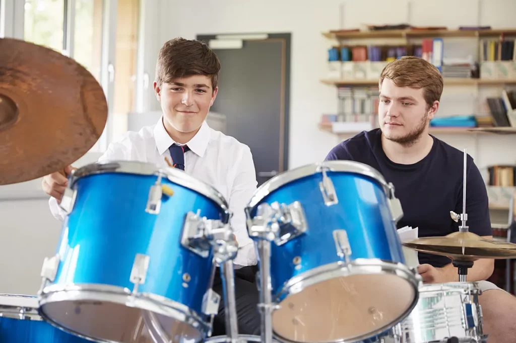 Young student learning drums with a teacher