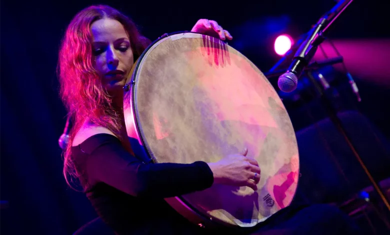 A female musician playing the frame drum with the Greek singer Psarantonis on stage in Warsaw.