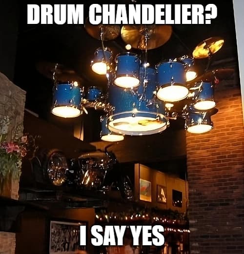 A drum set chandelier, hanging from the ceiling of a bar, complete with cymbals